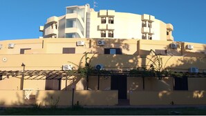 A multi-story building with balconies, air conditioning units, and a pergola with climbing plants. - Villaggio La Feluca (Isca sullo Ionio)