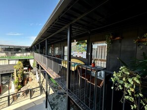 A covered outdoor area with a metal railing, potted plants, and a yellow chair. - Pousada Canto do Gravatá (Penha)