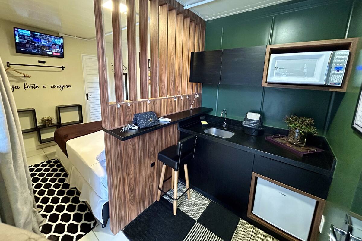 A modern bathroom with a wooden vanity, a black sink, a mirror, and a television mounted on the wall.