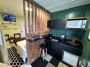 A modern bathroom with a wooden vanity, a black sink, a mirror, and a television mounted on the wall. - Pousada Canto do Gravatá (Penha)