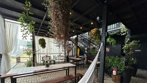 An indoor dining area with brick flooring, tables, chairs, and hanging plants. - Pousada Canto do Gravatá (Penha)