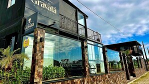 A two-story building with a large glass facade, a balcony on the upper floor, and a sign that reads "Cantó de Gravata". - Pousada Canto do Gravatá (Penha)