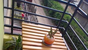 A balcony with a wooden table, a potted plant, and a chair.