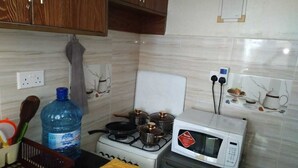 A kitchen with a stove, pots, a microwave, and a water dispenser.