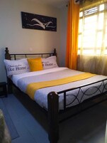 Una cama con una colcha blanca y amarilla, dos almohadas y un cabecero negro.