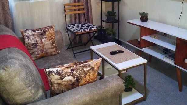 A living room with a sofa, a coffee table, a TV, and a window with curtains.