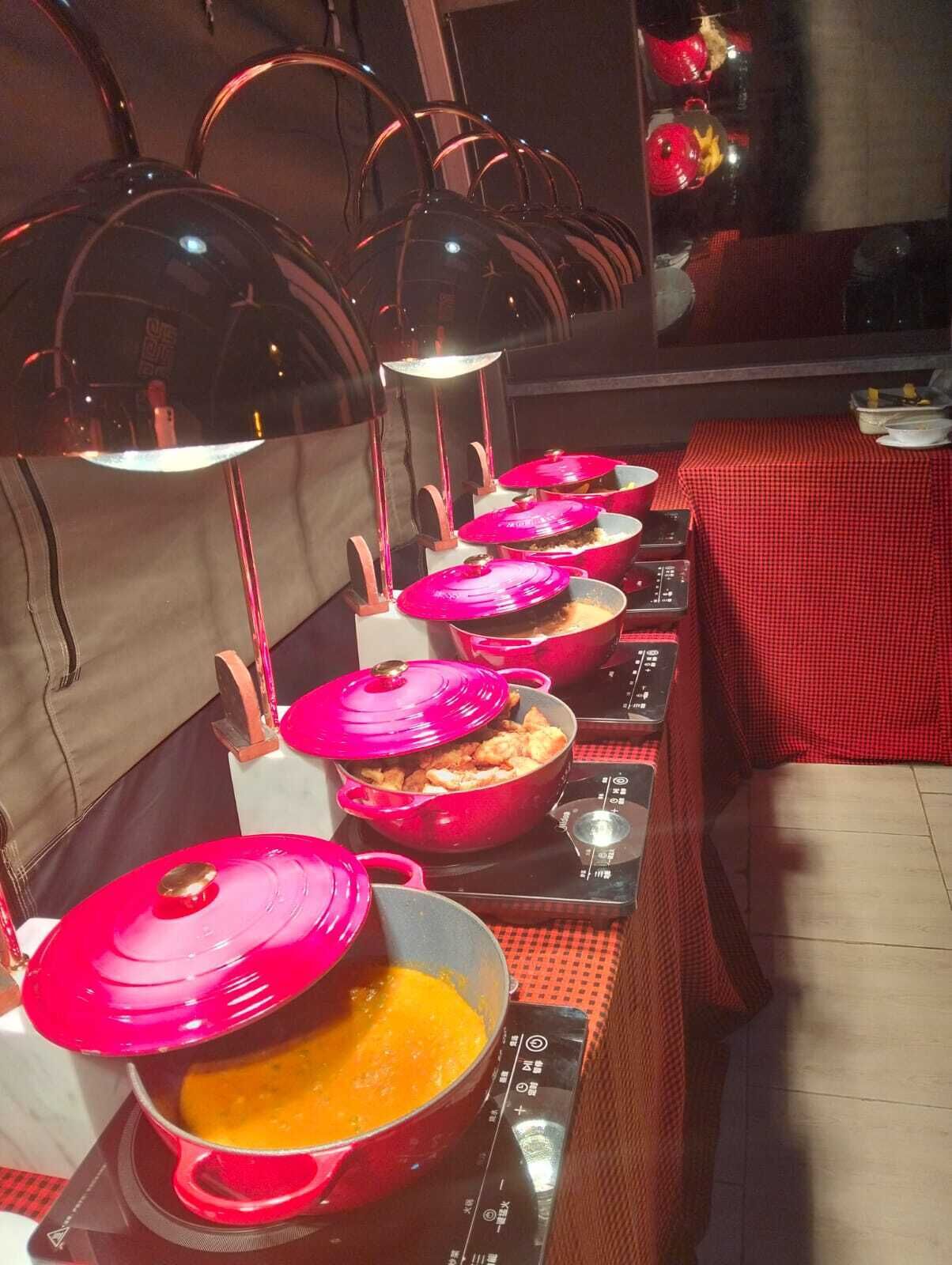 A row of red pots on induction cooktops, likely in a restaurant or kitchen area.