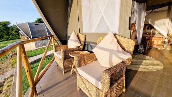 Wicker furniture with cushions on a balcony with a view of the outdoors.