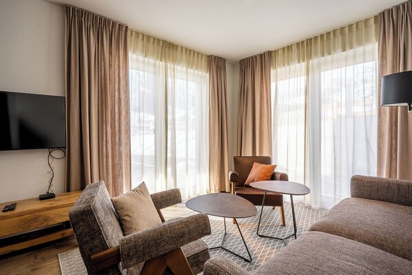 A modern living room with a flat-screen TV, a wooden coffee table, and two sofas.