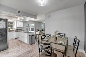 A modern kitchen with a dining area, wooden flooring, and a built-in island. - Luxury Home w/ Heated Pool & Golf Access (Scottsdale)
