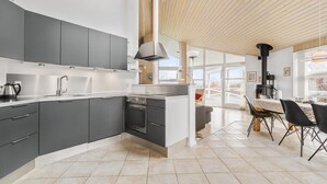 Una cocina moderna con armarios grises, un horno empotrado y un ventanal amplio.
