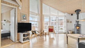 Un salón amplio con un televisor grande, suelo de madera y chimenea.