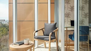Una habitación moderna con vistas, una silla de madera, una mesita pequeña y una silla azul.