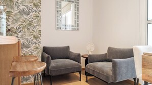 Una habitación con dos sillones grises, una mesa de madera y un espejo en la pared.