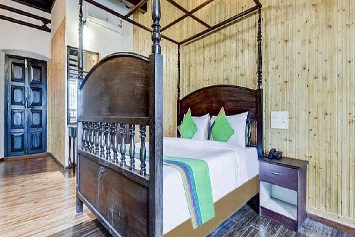 A four-poster bed with a wooden headboard, a bedside table, and a nightstand.