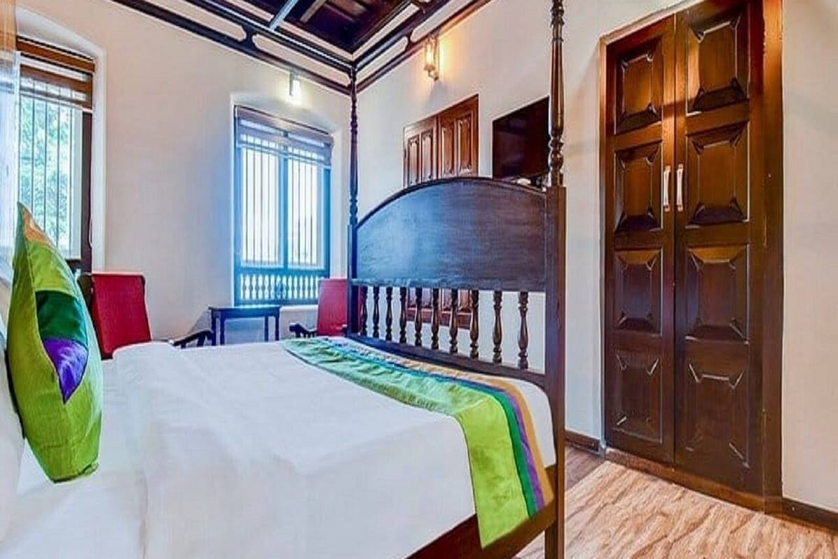 A bedroom with a bed, a window, a wardrobe, and a door.