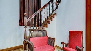 A living room with a wooden staircase, a sofa with red cushions, and a glass coffee table. - AVVA Hotels (Kochi)