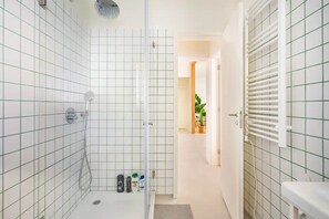 Bathroom features a shower area with a glass door and a tiled grid pattern.
