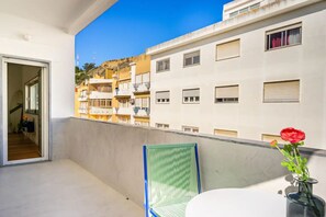 Enjoy the serene view from this balcony with a single chair and a beautiful flower arrangement.
