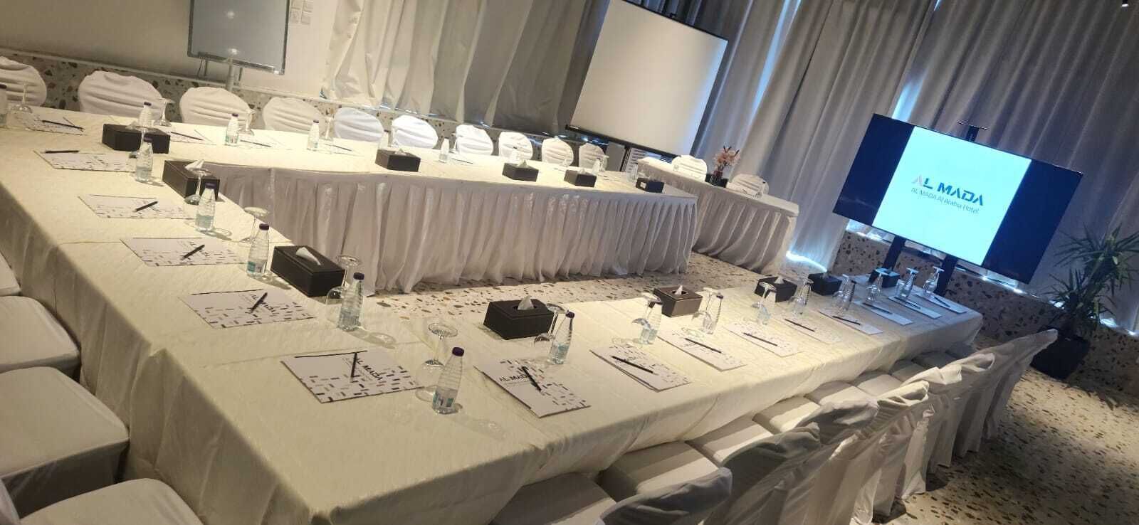 A conference room with a long table set for a meeting, equipped with nameplates, water bottles, and notepads.