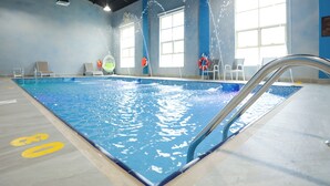 Una piscina interior con agua cristalina, un trampolín y un puesto de socorrista.