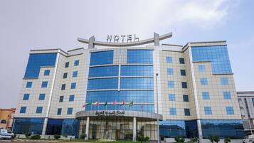 A modern hotel with a prominent 'HOTEL' sign at the top, featuring a glass facade and multiple flags.