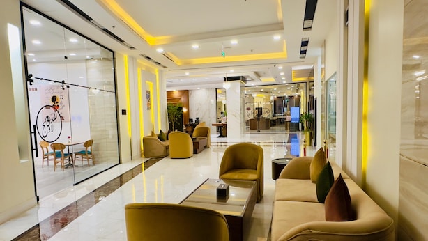 Un vestíbulo moderno con asientos amarillos, un mostrador de recepción y un muro de cristal con un cartel.