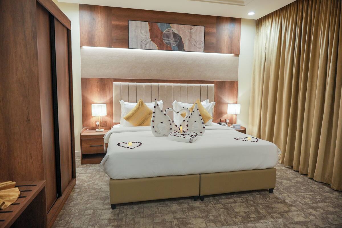 A hotel room with a large bed, two bedside tables, a headboard, and a wall-mounted artwork.