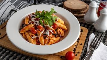 A plate of pasta with a garnish, placed on a wooden board with a striped cloth underneath.