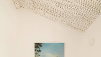 A bedroom with a bed, a painting of a landscape, and a sloped ceiling.