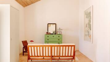 Una habitación con un banco de madera, un aparador verde, un espejo e impresión botánica enmarcada en la pared.
