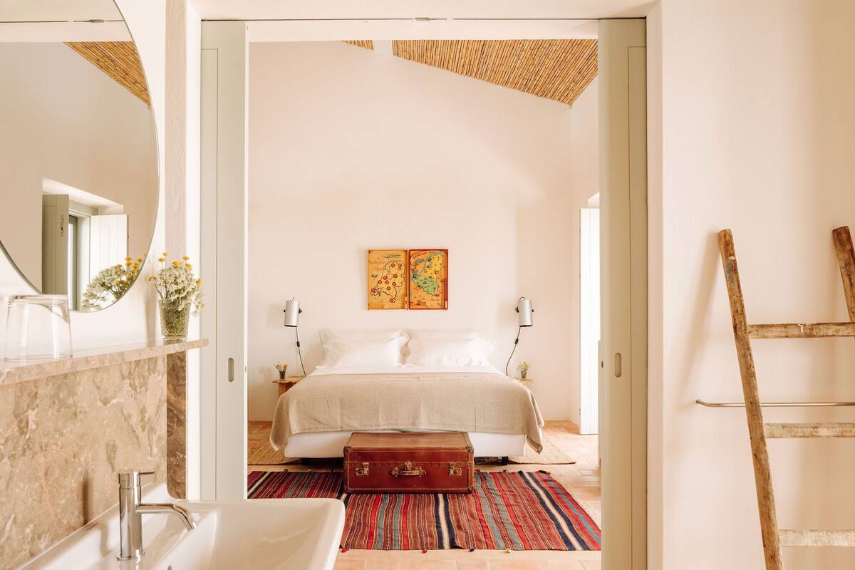 Quarto com cama, mala e mapa na parede.