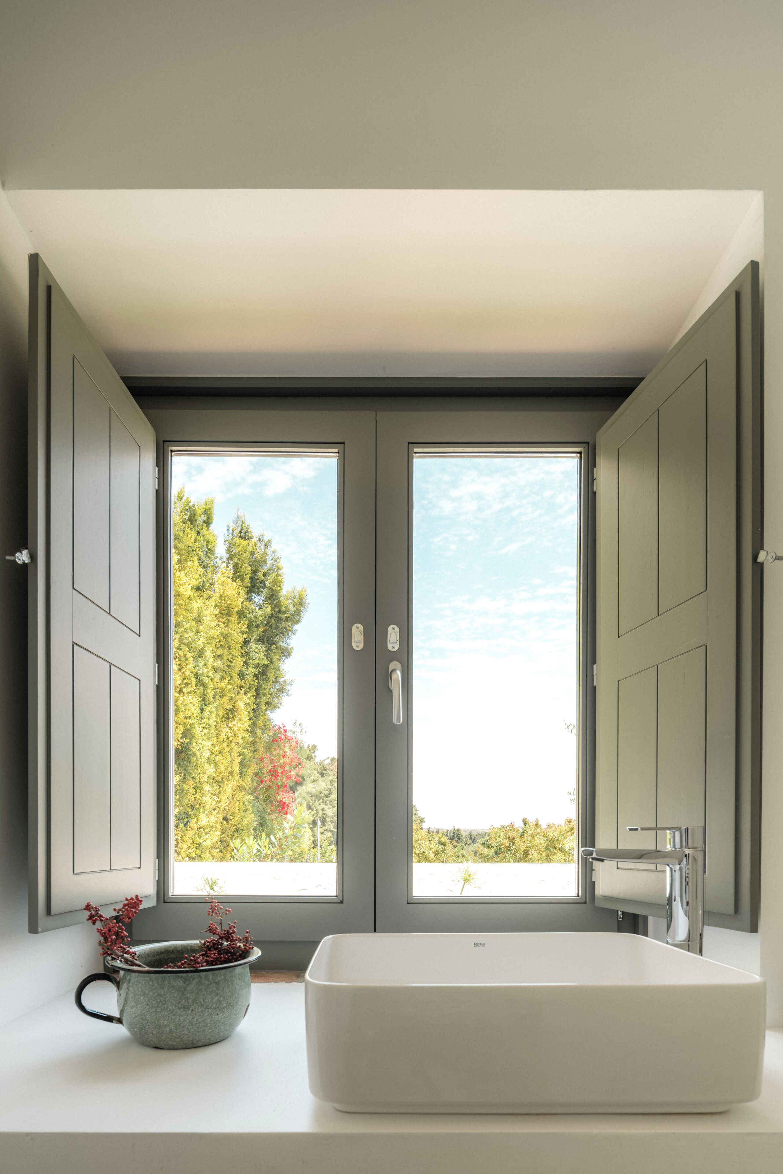A bathroom with a large window, a bathtub, and a sink.