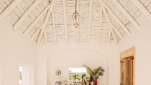 A rustic interior with a wooden ceiling, a wooden cabinet with glassware, and a window with a view of greenery. - Casas da Quinta de Cima (Vila Real Santo Antonio)