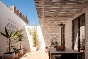 Eine moderne Terrassenanlage mit Tisch, Stühlen und Pflanzgefäßen.