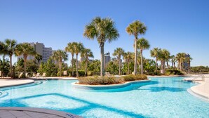 A swimming pool with palm trees and lounge chairs, surrounded by buildings. - Pool View ~ Oversized Balcony ~ Tram Included (Miramar Beach)