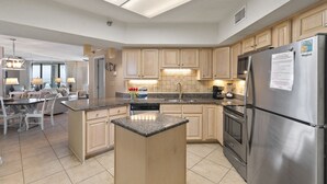 A modern kitchen with granite countertops, stainless steel appliances, and wooden cabinets. - White Caps 503 by Liquid Life (Orange Beach)