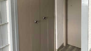 Una puerta cerrada con un picaporte sencillo y una cerradura, una pared blanca con textura y un suelo de madera.