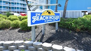 Une enseigne pour « The Beach House at Garden City », avec un fond bleu et un soleil jaune.