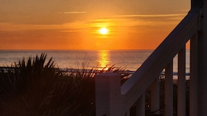 Un coucher de soleil sur l’océan, avec une vue sur la mer et un escalier qui descend.