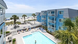 Un espace piscine avec des chaises longues et vue sur la plage.