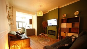 A living room with a sofa, a coffee table, a TV, and a fireplace. - L Arbre d or Appart Hyper Centre SPA Couvert (Cambrai)
