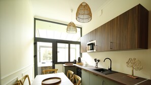 A modern kitchen with wooden cabinets, a built-in microwave, a sink, and a dining area with a wooden table and chairs. - L Arbre d or Appart Hyper Centre SPA Couvert (Cambrai)