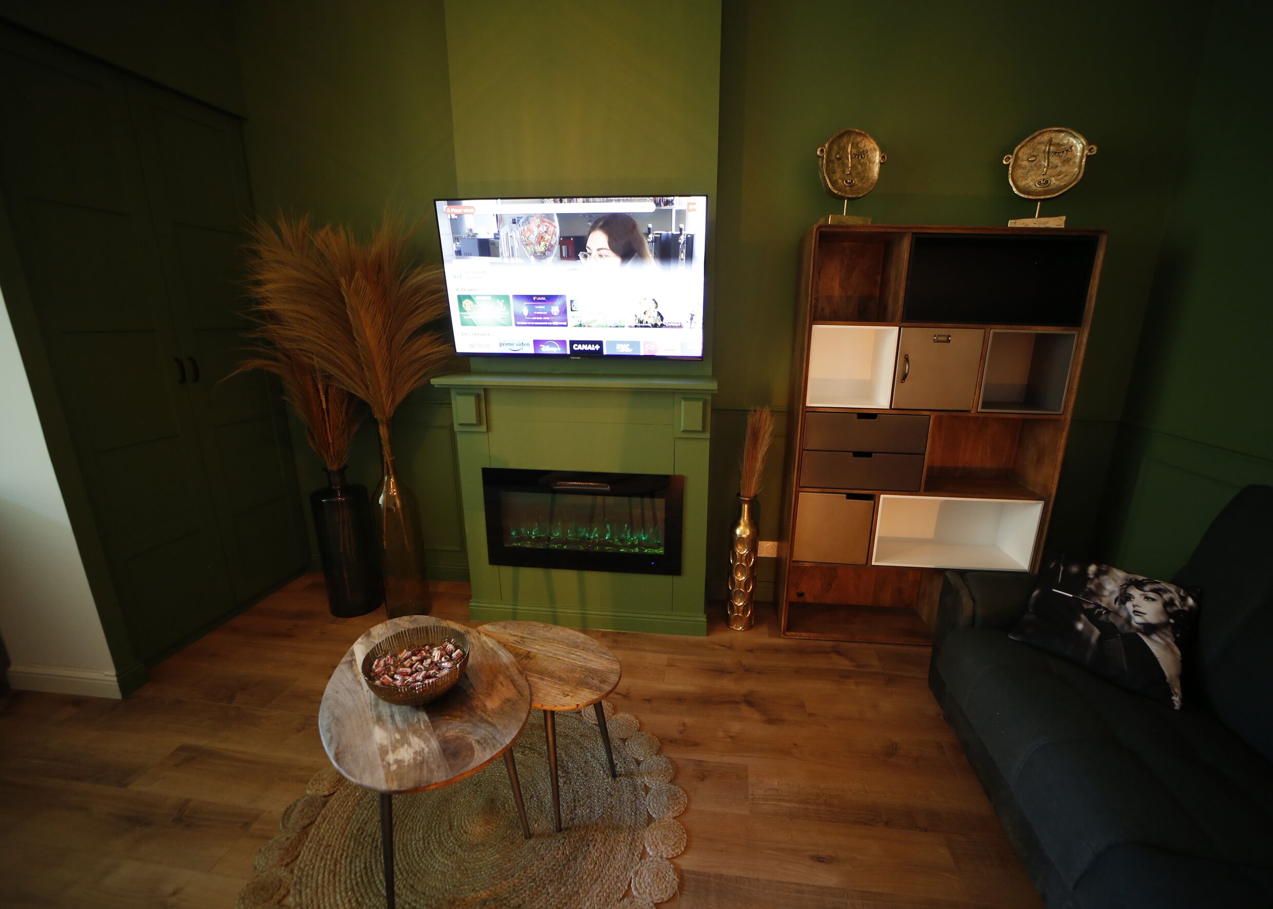 Een woonkamer met een televisie, een open haard, een bank en een decoratieve plank.