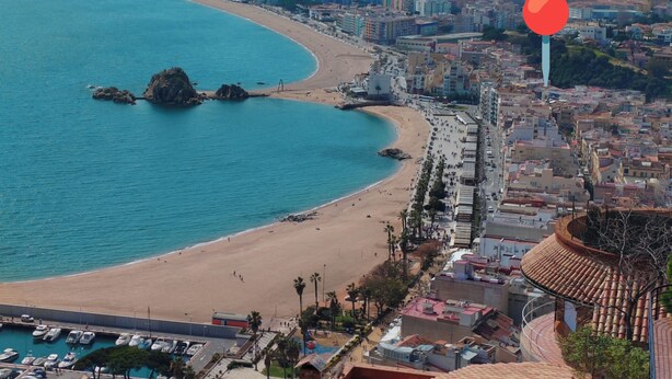 A coastal cityscape with a beach, buildings, and a marina.