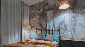 A bedroom with a bed, a nightstand, a dresser, and a wall with a stone-like texture.