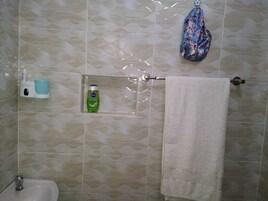 Un baño con pared de baldosas estampadas, un lavabo, un perchero para toallas y una bolsa colgante.