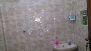 A small bathroom with a shower, a sink, and a toilet. - Lux Suites Vet Studio Apartments (Ngong)