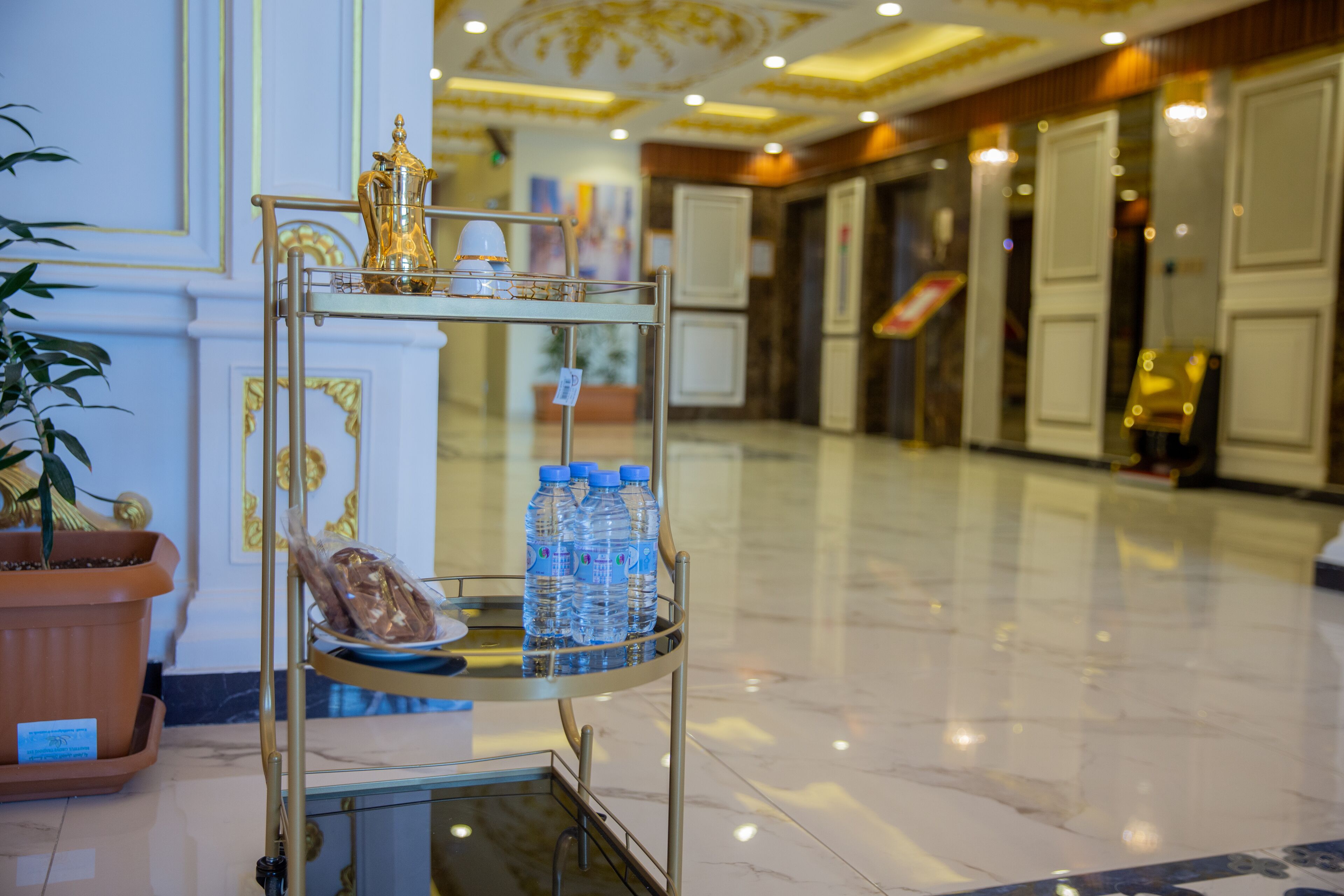 A lobby with a metal cart holding water bottles and a tray with bread.
