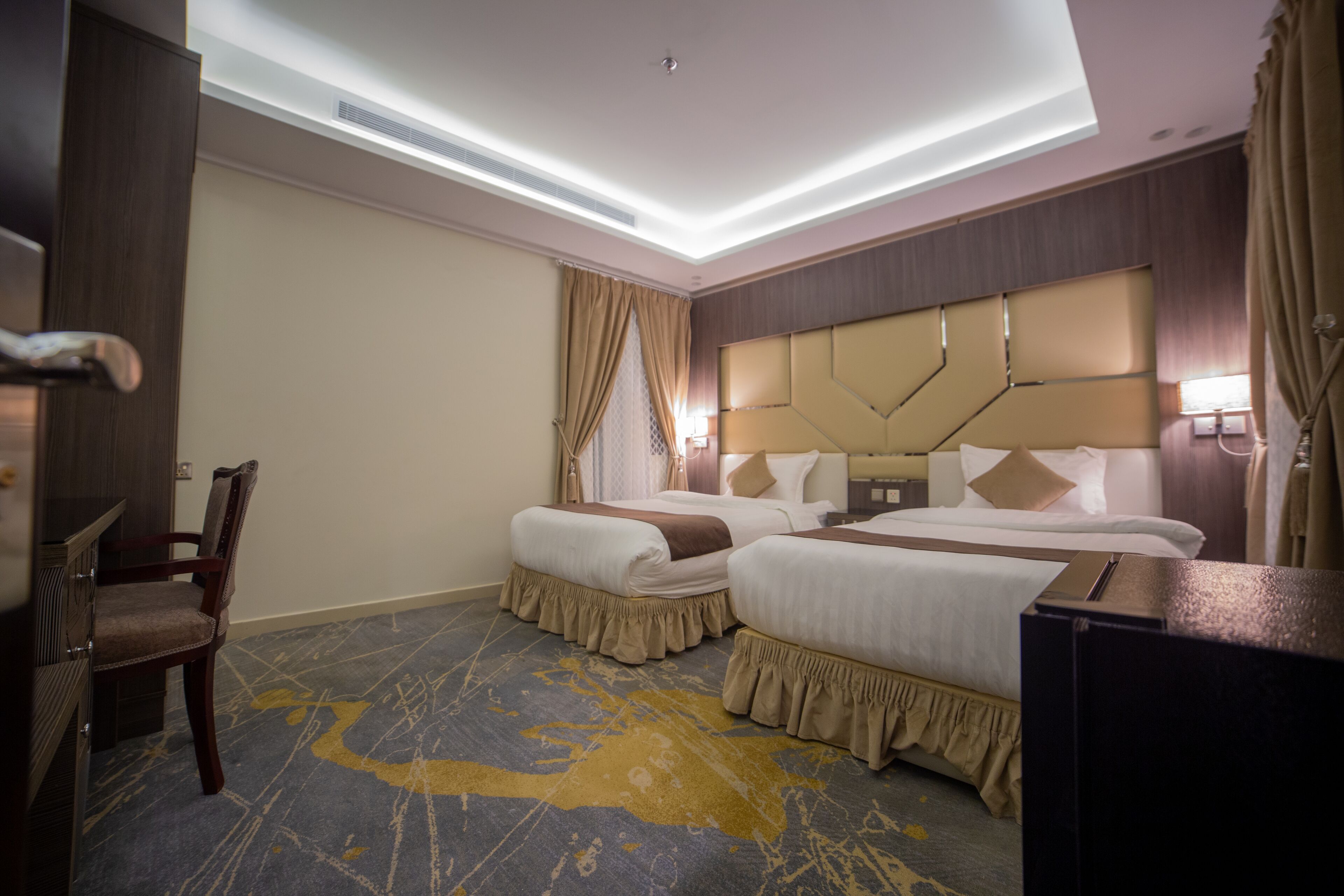 A hotel room with two beds, a desk, and a chair.